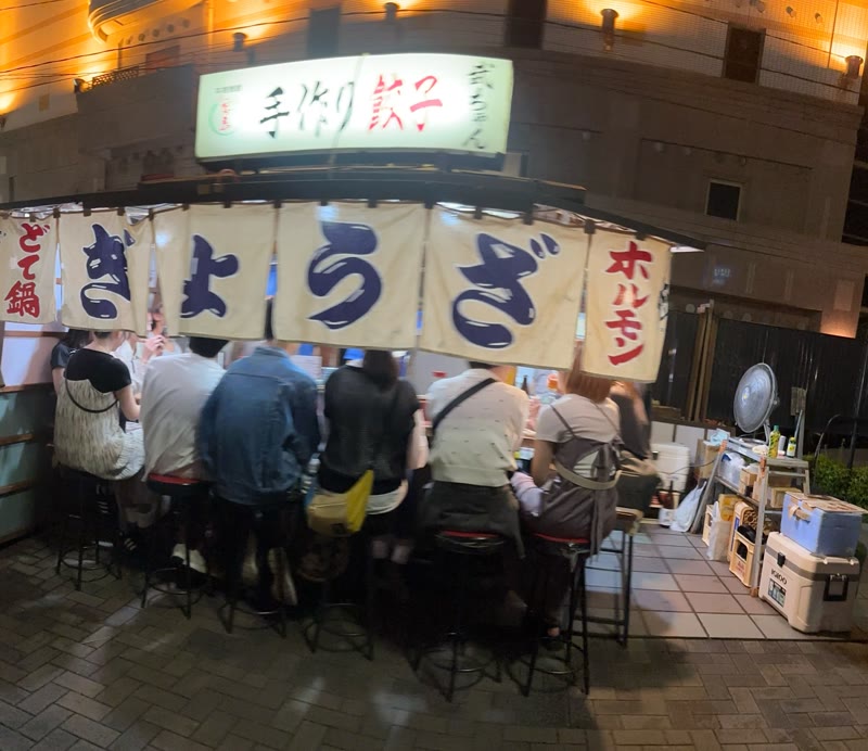 A yatai food stall at night in Fukuoka, customers along the counter